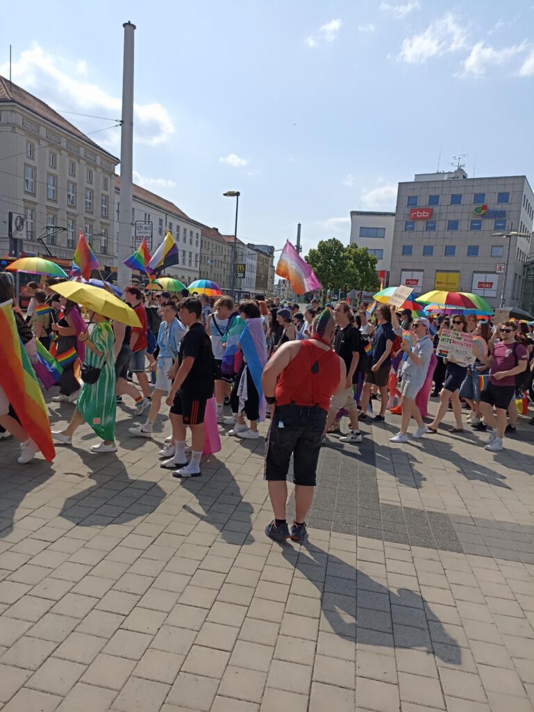 Demozug blockiert Straßenbahn den weg. Im Hintergrund ist ein Gebäude des RBB.